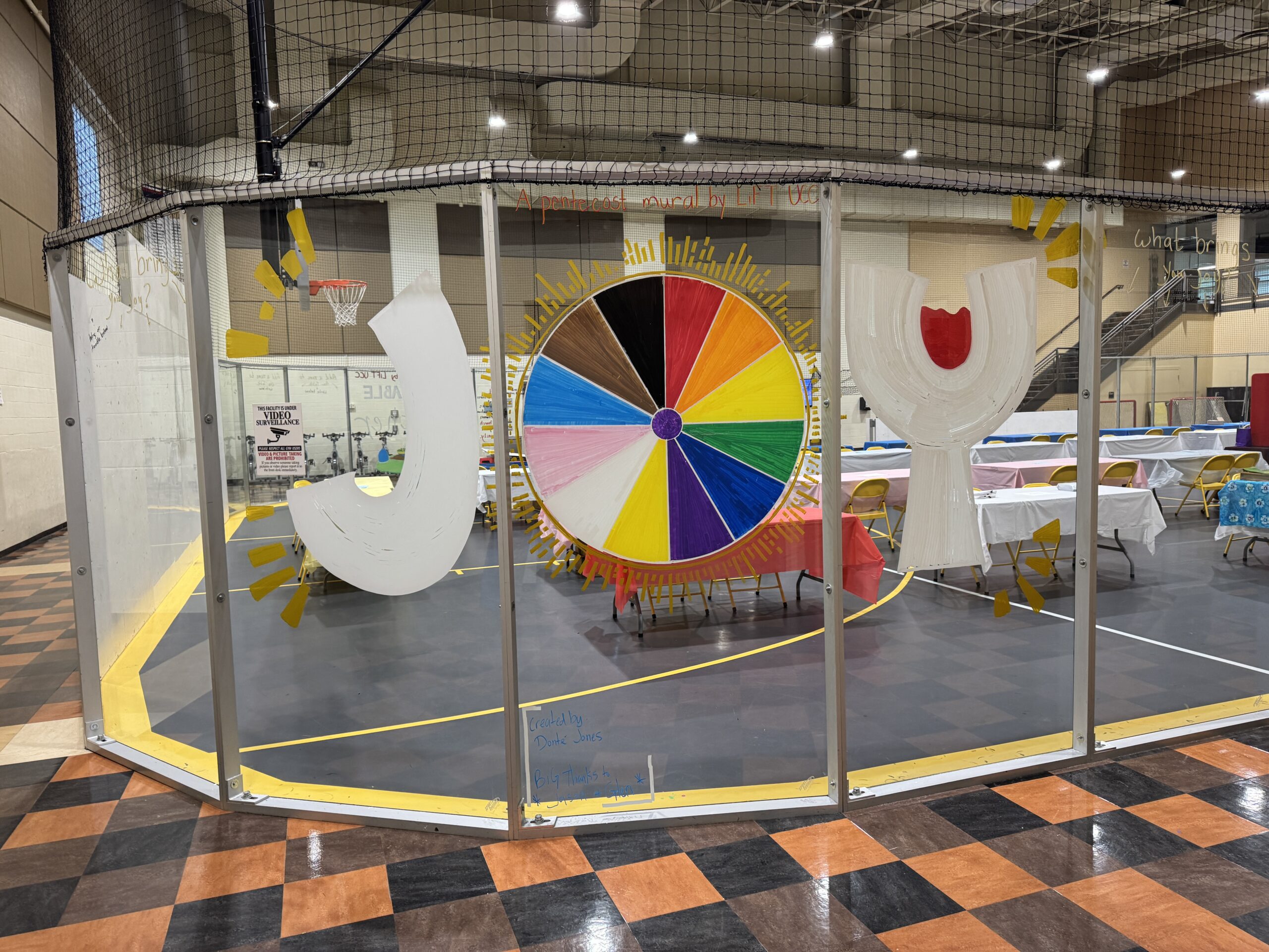 A window painting with the word JOY, the letter O represented by a colorful startburst