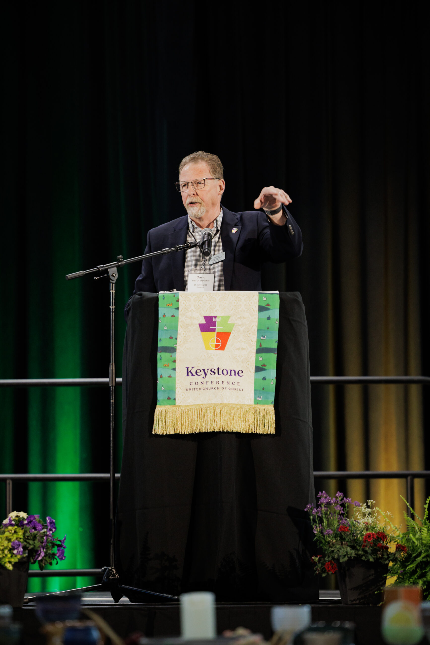 Board Moderator Rev. Dr. David DeRemer stands behind podium with Keystone Conference logo