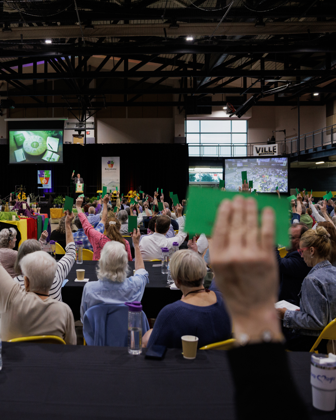 Room full of raised hands with green "yes vote" cards